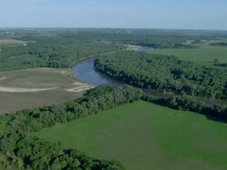 Winding river surrounded by trees and fields Stock Footage