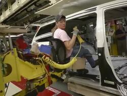 MS PAN Worker uses an ergonomically designed sled to help her move inside mini-van as she installs accessories / Princeton, Indiana, United States Stock Footage