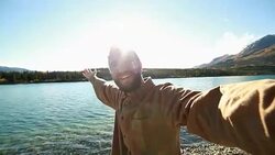 Cheerful man in nature takes selfie portrait near lake Stock Footage