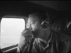 1952: SMALL AIRCRAFT COCKPIT: CU Unidentified male, sitting in cockpit co-pilot seat next to right window, wearing headphones, speaking into hand-held mic (No SOT), looking out & down through side window. Instructional Video