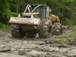 Slow motion full shot of skidder as it moves through the mud toward the camera into a close up of the wheels. Stock Footage