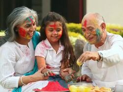 Senior man feeding rasgulla to his granddaughter in holi festival  Stock Footage