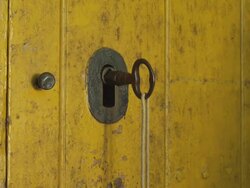 ECU hand of man turns big key in closed wooden door, pushes door open to reveal an almost black room Stock Footage