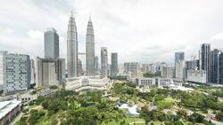 Clouds move over the Petronas Twin Towers and a nearby park in Kuala Lumpur, Malaysia. Stock Footage