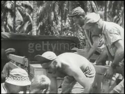 1943: BOUGAINVILLE CAMPAIGN: VS U.S. Army soldier unloading crates, supplies, from back of wagon in forest of Solomon Islands, stockpile of bomb shells across forest field, Jeep driving BG. MS Sign post 'Sightseers... will be prosecuted.' WWII Instructional Video