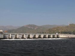 Dam is draining stream of water with mountain background Stock Footage