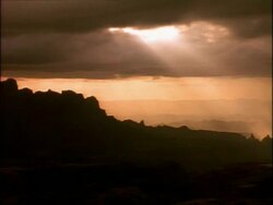 WA pan right across silhouetted mountain range of Simian mountains, sunlight bursting through clouds at dusk, Ethiopia, Africa Stock Footage