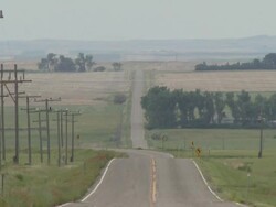 Shot looking along straight road, across prairie and farm land, USA. Stock Footage
