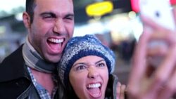 Young couple make funny faces taking photos together with smartphone in Times Square Stock Footage