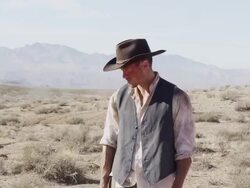 Cowboy standing there looking off to the side then looks at the camera as it zooms into a tight shot of his face. Stock Footage