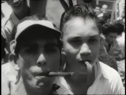 B/W May 13, 1958 The Caracas Incident During Nixon's Tour - MEDIUM SHOT crowd of people holding Go Away Nixon sign outside of Caracas airport / MEDIUM SHOT crowd holding We Don't Want Nixon sign / MEDIUM SHOT young man holding caricature of Nixon in crowd News Clip