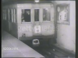 1942: TOKYO, JAPAN: * WS Two Japanese females, in kimonos, entering into subway station, pedestrians & automobiles BG. INT WS Underground train pulling into platform. VS People filing into train, passing ticket man, exiting train station to street. Instructional Video
