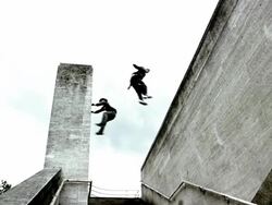 Low angle wide shot two freerunners jumping to opposite walls Stock Footage
