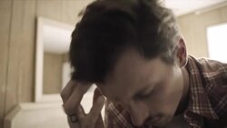 Tormented young man runs his hand through his hair as young woman paces in background Stock Footage