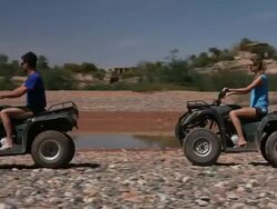 Good Looking Young Couple ride Quad Bikes in desert Stock Footage
