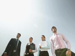 Four business people standing on the cliff of mountain Stock Footage