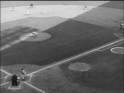 B/W 1955 high angle Johnny Podres pitching to Yogi Berra who hits ball + runs to first base / World Series Stock Footage