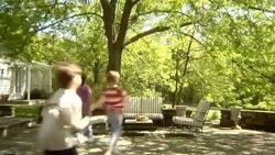 WS, USA, New York State, Bedford Hills, three children (6-9 years) running up and seating at outdoor seating area in back garden Stock Footage