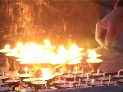 Buddhist monk lights butter lamps (candles). Stock Footage