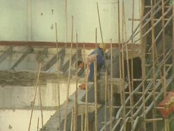 MS Shot of building site with bamboo scaffolding, workers demolishing wall / Shanghai, China Stock Footage