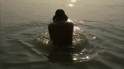 An old man bathes in a sea in India at sunset. Stock Footage