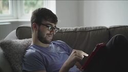 Using digital tablet, sitting comfortably on a sofa. DS Stock Footage