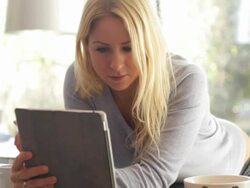 Young female looking at ipad and drinking tea in kitchen Stock Footage