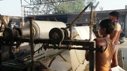 Workers wash and roll newly dyed fabric at the Sari garment factory in Jaipur, India. Stock Footage