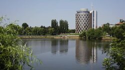 A modern, cylinder-shaped office building overlooks a quiet pond. Stock Footage