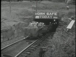 Coal miners enter a coal mine tunnel under a sign for safety. News Clip