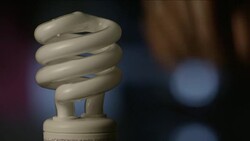 A CFL light bulb is twisted in and out of a socket, switching on and off. Stock Footage