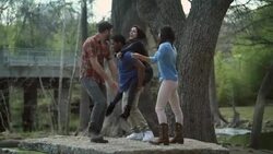 Group of friends goof off and dance on flat rock in scenic riverside park Stock Footage