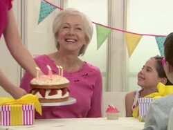 Senior woman blowing out candles on cake at birthday party with family Stock Footage