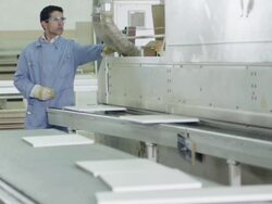 worker feeding panes of fibreboard into processing machine in furniture factory Stock Footage