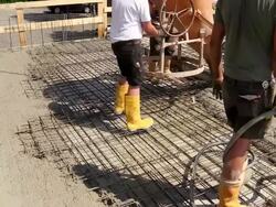 MS Shot of workmen working cement spreding on floor from cement bucket at construction site / Hermeskeil, Rhineland Palatinate, Germany Stock Footage