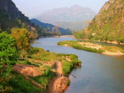 WS View of river bank with people walking by and mountains / Nong Khio, Luang Prabang, Laos Stock Footage