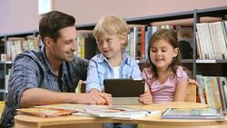 DS Father looking at kids using tablet in library Stock Footage