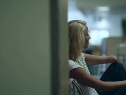 Panning slow motion shot of teenage girl sitting by locker missing part of left arm. Stock Footage