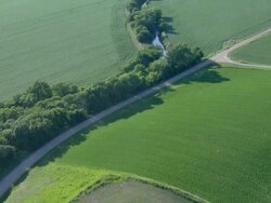 Gravel road in the country surrounded by fields and a farm house Stock Footage