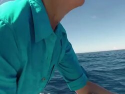 CU Shot of Woman reeling sport fishing tackle rod on boat with man taking photo in background / Iztapa, Guatemala Stock Footage