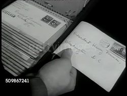 1947: U.S. PROTECTIVE RESEARCH DEPARTMENT: VS Men at table, filing cabinet, examining letters. CU Flipping through filed letters. DRAMATIZATION: VS Men in lab putting letter into solution (latent image), letter showing fingerprints. Washington D.C. Instructional Video