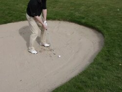 Man chipping out of sand bunker, UK Stock Footage