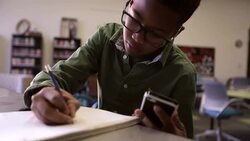 Schoolboy doing homework with cell phone in library Stock Footage