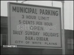 1949: WHITE PLAINS PARKING LOT: WS Car pulling into parking lot. CU Sign 'Municipal Parking 3 Hour Limit 5 Cents per Hour.' WS White Plains parking lot, car pulling into spot, parking meters. MS Woman paying parking meter. CU Inserting nickel. Instructional Video