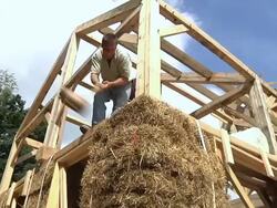 WS ZO Carpenter using large mallet and level on bales of straw during framing of an energy efficient post / Grass Lake, Michigan, USA  Stock Footage