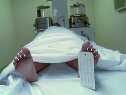 Medium shot teenage girl's corpse lying on table in morgue with toe tag Stock Footage