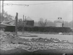B/W 1956 wide shot PAN Soviet tanks speeds down street past civilians / Hungarian uprising Stock Footage