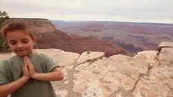 Young boy closes eyes and prays in front of Grand Canon (pan) Stock Footage