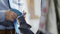 Shop employee tags shirtsleeves in clothing store with tagging gun Stock Footage