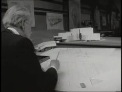 Architect Frank Lloyd Wright works at a drafting table. News Clip